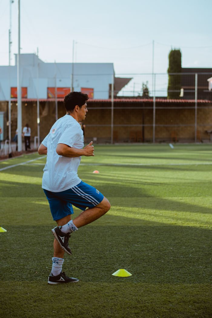 A young male athlete in a sports field during daylight practice.